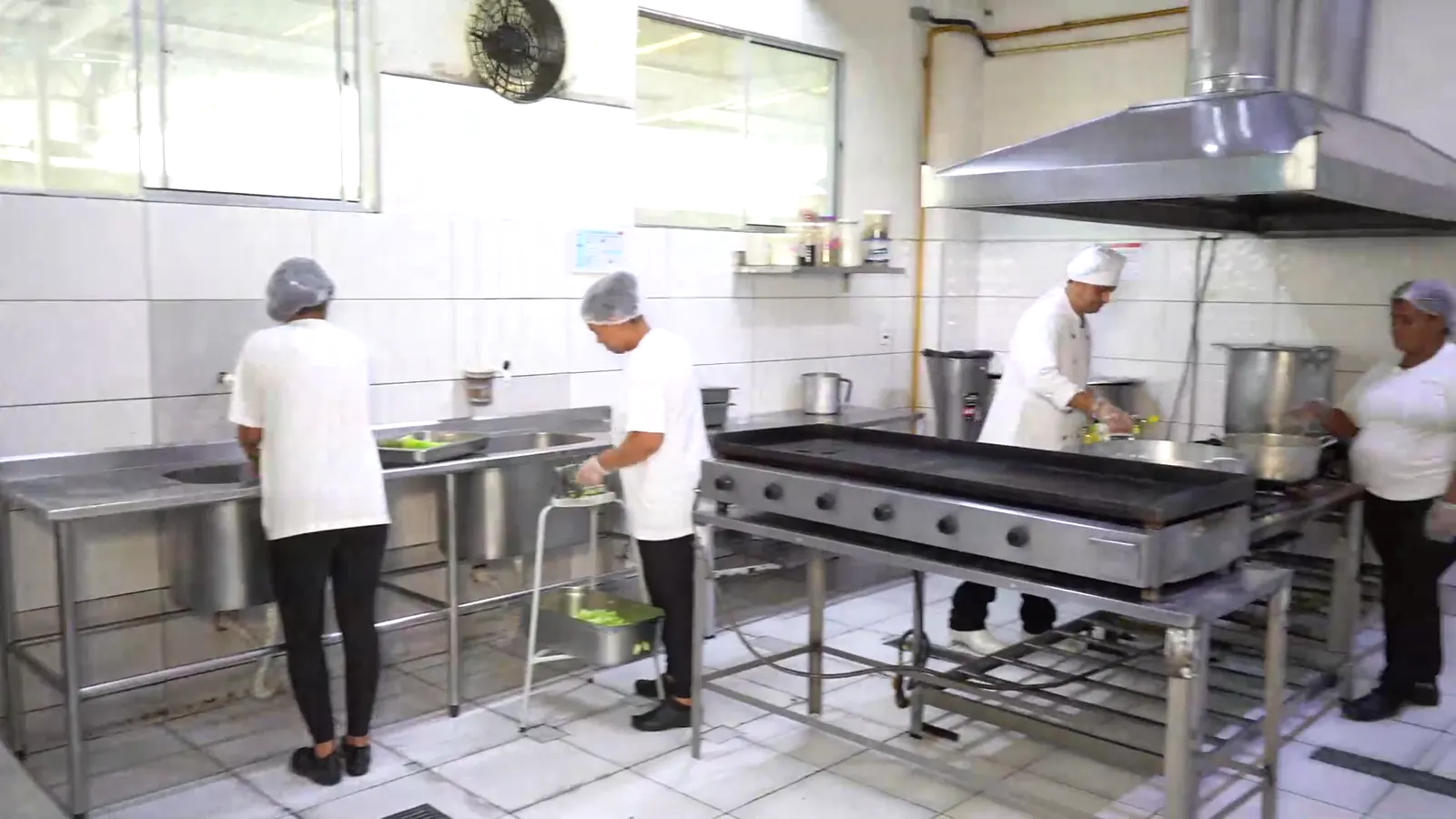 Equipe de touca preparando refeições na cozinha industrial da Gran Vitória